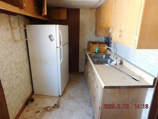 kitchen with white fridge, sink, a paneled ceiling, and backsplash