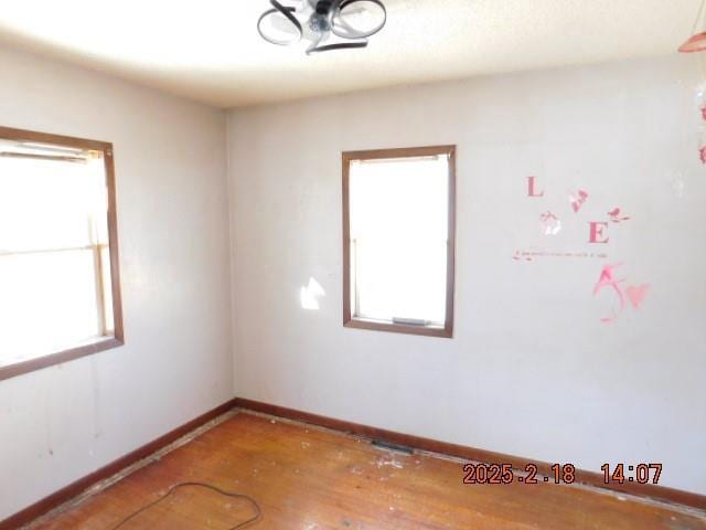 empty room with a wealth of natural light and hardwood / wood-style flooring