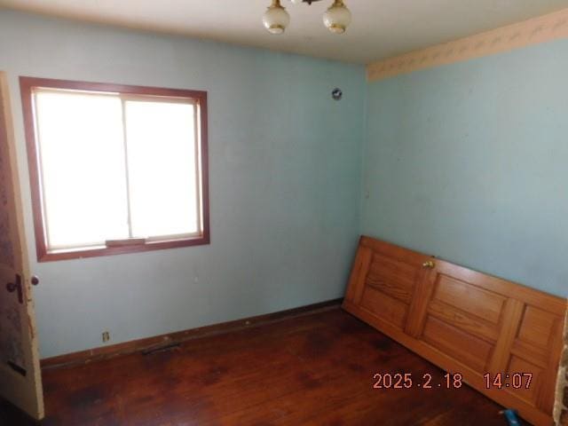 unfurnished room featuring a notable chandelier and dark hardwood / wood-style floors