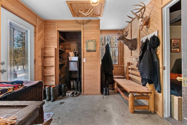 mudroom with concrete flooring and wooden walls