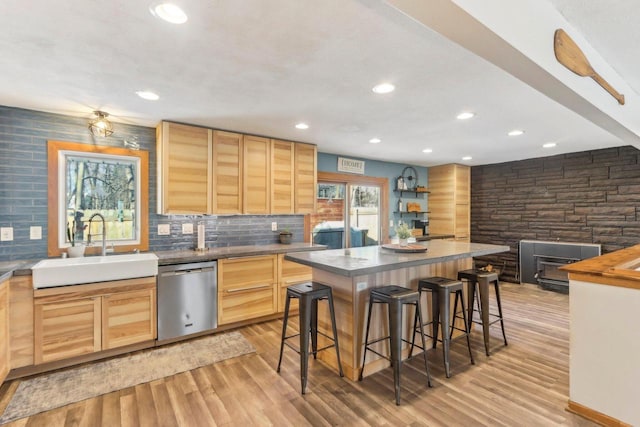 kitchen with sink, light brown cabinetry, a kitchen island, a breakfast bar area, and dishwasher