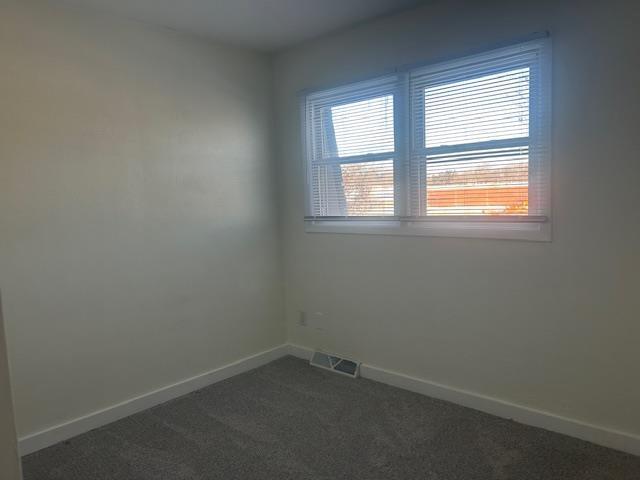 unfurnished room with dark carpet