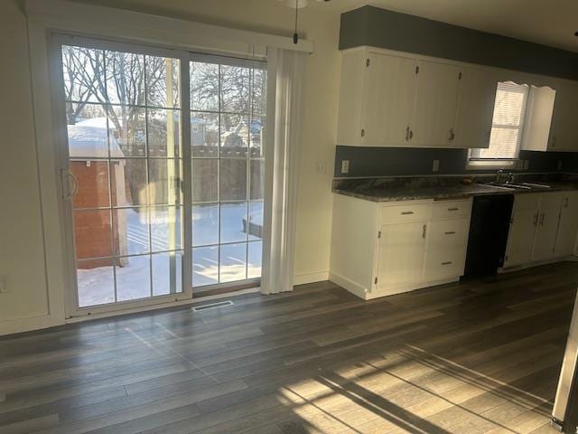 kitchen featuring black dishwasher, dark hardwood / wood-style flooring, sink, white cabinetry, and dark stone countertops