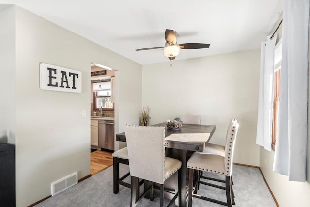 dining room featuring sink, light carpet, and ceiling fan