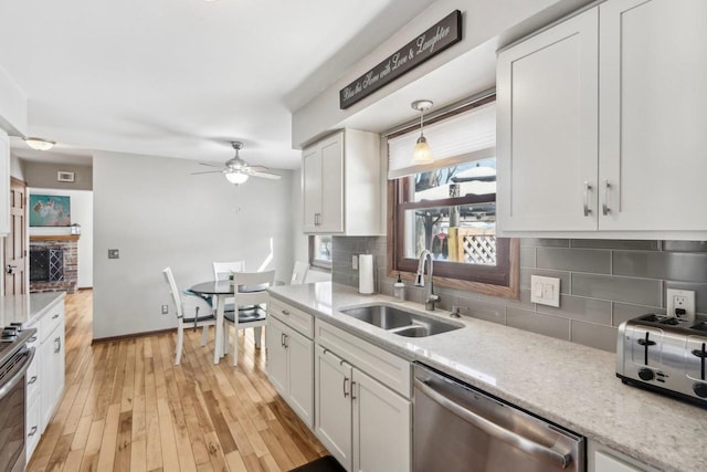 kitchen with stainless steel appliances, white cabinets, decorative light fixtures, backsplash, and sink