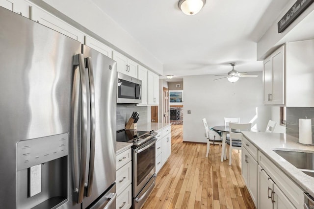 kitchen featuring white cabinetry, appliances with stainless steel finishes, light wood-type flooring, and light stone counters