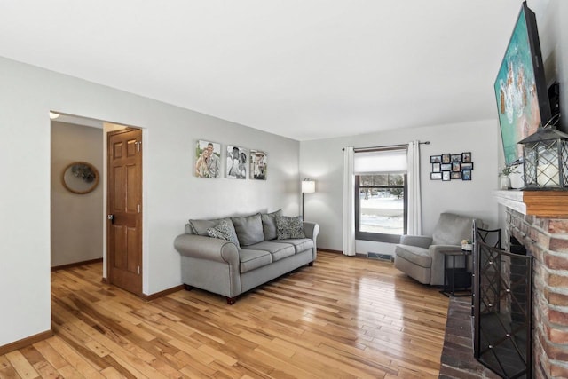 living room featuring light wood-type flooring and a brick fireplace