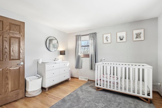 bedroom featuring light hardwood / wood-style flooring and a nursery area