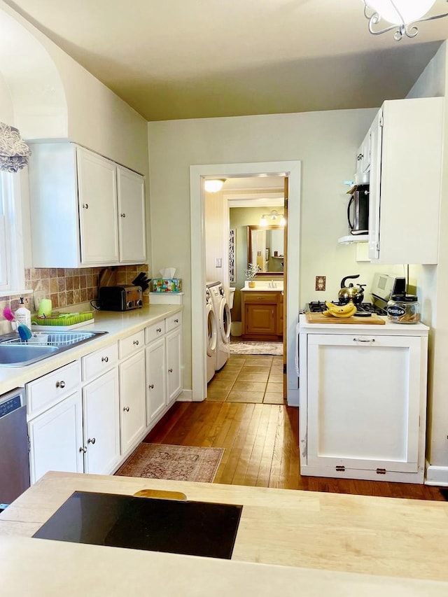 kitchen with tasteful backsplash, stainless steel appliances, washing machine and dryer, sink, and white cabinetry