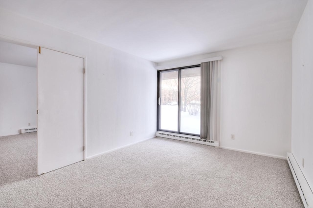 spare room featuring carpet flooring and a baseboard heating unit