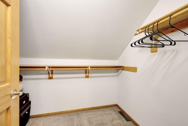 spacious closet with light carpet, lofted ceiling, and visible vents