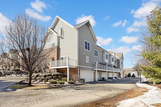 view of home's exterior with central air condition unit, an attached garage, a residential view, and brick siding