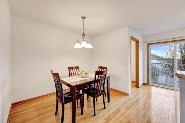 dining room with light wood-type flooring, an inviting chandelier, and baseboards