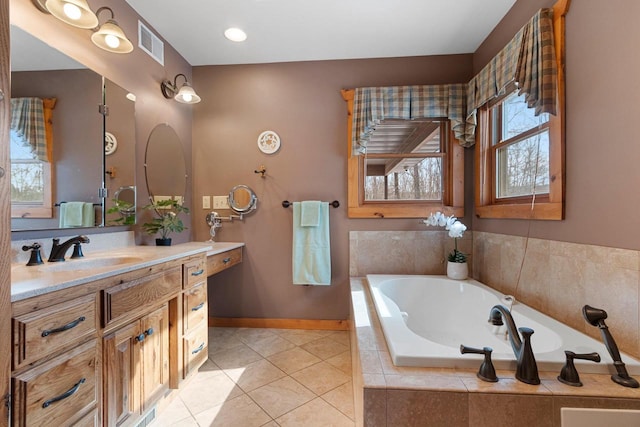 bathroom featuring tile patterned floors, vanity, and a relaxing tiled tub