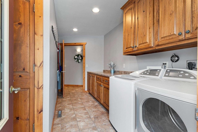 clothes washing area featuring washing machine and dryer and cabinets