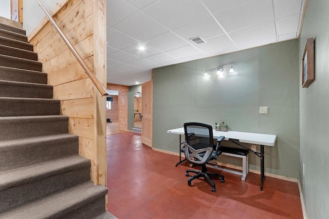 home office featuring a drop ceiling and concrete flooring