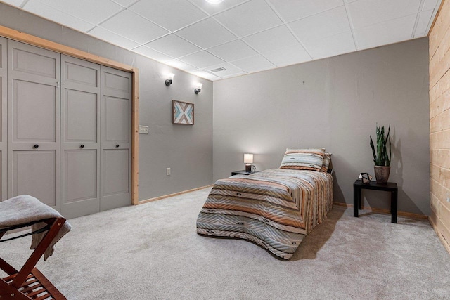 bedroom with light carpet and a drop ceiling