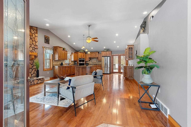 living room with high vaulted ceiling, ceiling fan, and light hardwood / wood-style flooring