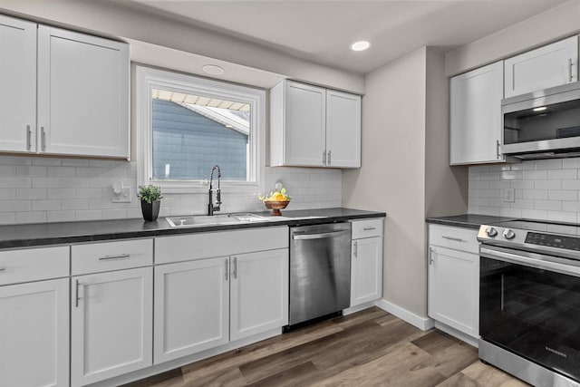 kitchen featuring appliances with stainless steel finishes, sink, dark wood-type flooring, white cabinets, and decorative backsplash