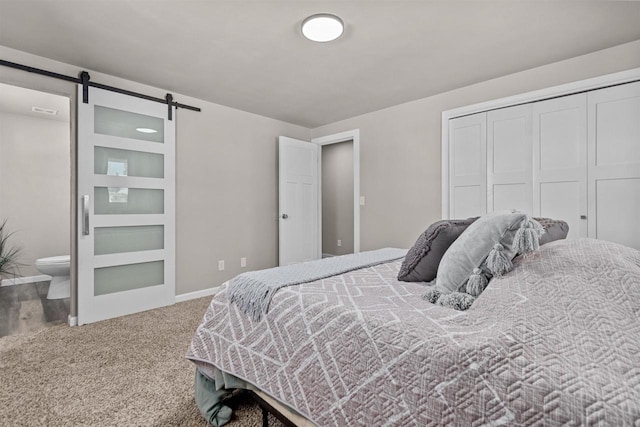 carpeted bedroom with a closet, ensuite bathroom, and a barn door