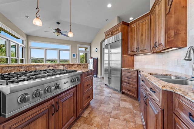 kitchen featuring sink, pendant lighting, a healthy amount of sunlight, stainless steel appliances, and light stone countertops