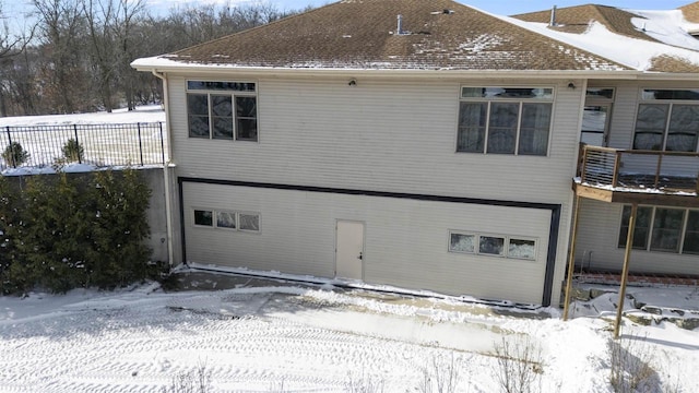 snow covered back of property featuring a garage