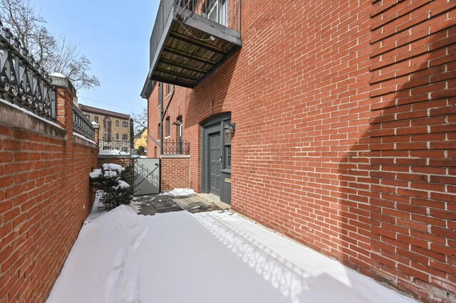 1442 N Franklin Pl Unit 2, Milwaukee, WI 53202 - snow covered property with a gate, brick siding, and fence