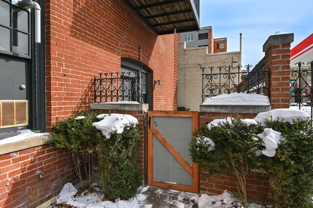 1442 N Franklin Pl Unit 2, Milwaukee, WI 53202 - view of snowy exterior with brick siding and a gate