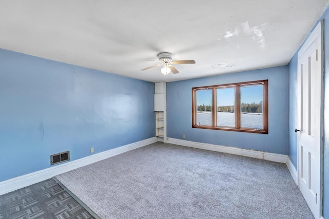 unfurnished room with dark colored carpet and ceiling fan