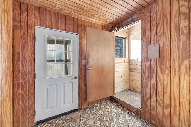 doorway featuring wooden walls and wood ceiling