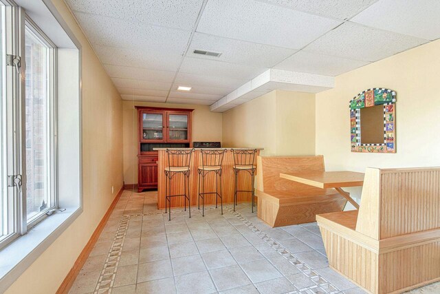 bar with a paneled ceiling and tile patterned floors