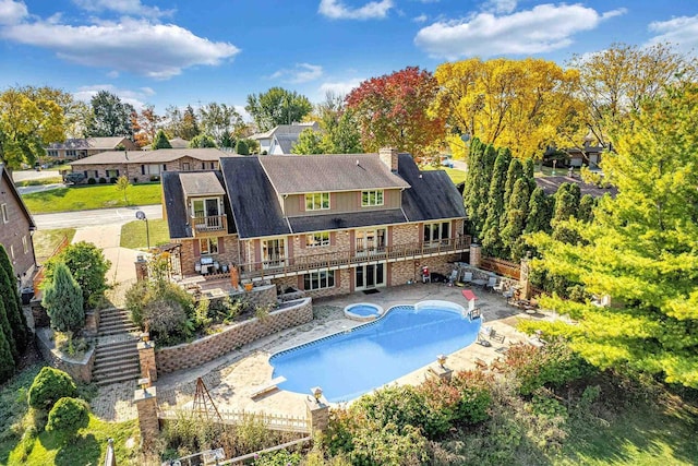 back of house with a patio area and a swimming pool with hot tub