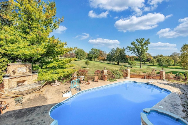 view of swimming pool featuring a patio area, a yard, and an outdoor stone fireplace