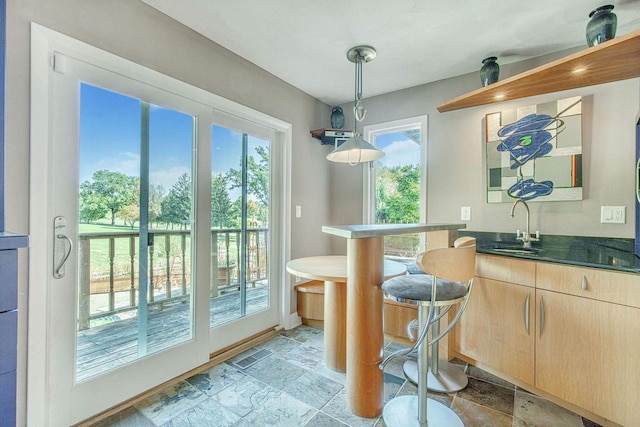 bar with sink, light brown cabinets, and pendant lighting