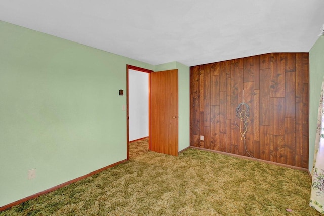 unfurnished room featuring carpet flooring and wood walls