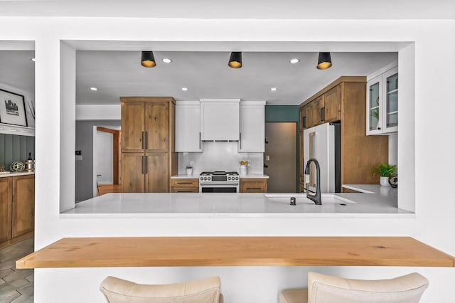 kitchen featuring kitchen peninsula, stainless steel appliances, white cabinetry, a breakfast bar, and sink