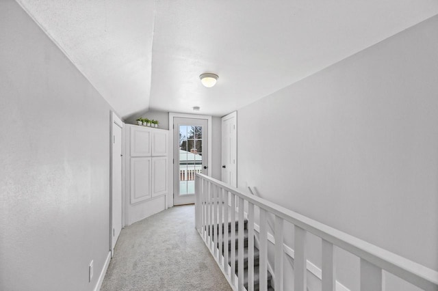 corridor featuring lofted ceiling and light colored carpet