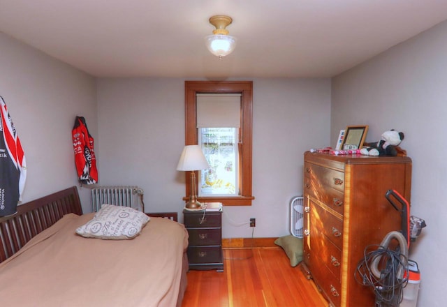 bedroom featuring radiator and hardwood / wood-style floors