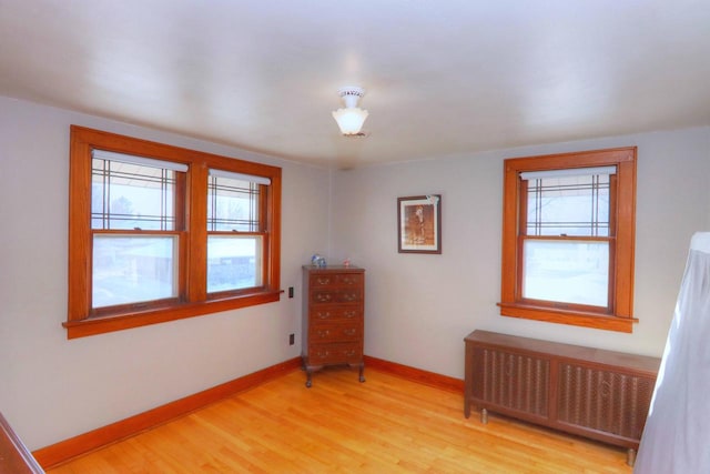 spare room with radiator heating unit, a wealth of natural light, and light hardwood / wood-style flooring