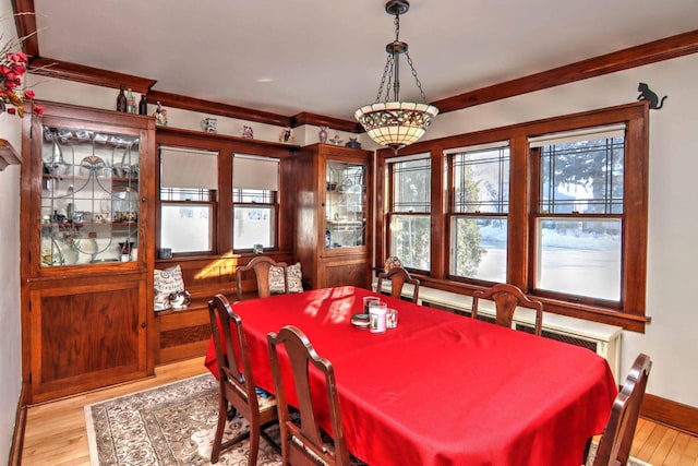 dining space featuring ornamental molding and light wood-type flooring