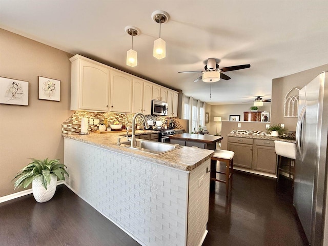 kitchen with sink, decorative light fixtures, stainless steel appliances, and kitchen peninsula