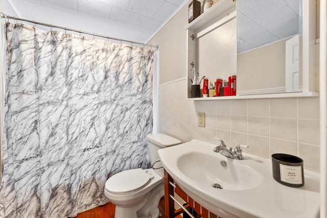 full bathroom featuring shower / bath combo, sink, tile walls, and toilet