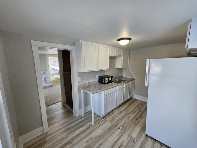 kitchen featuring sink, white fridge, light wood-type flooring, and white cabinetry