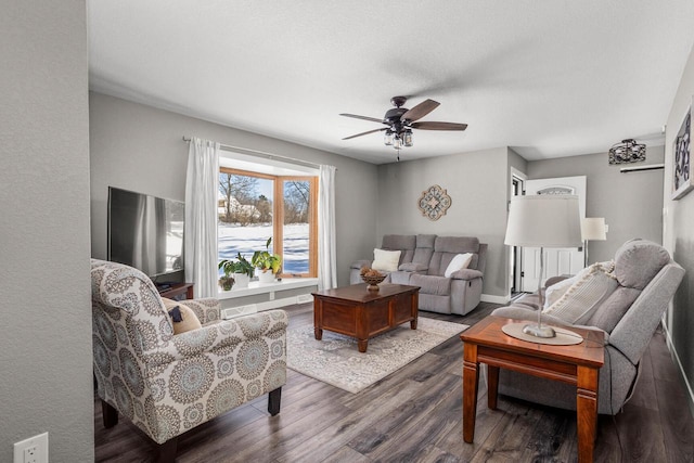 living room with dark wood-type flooring and ceiling fan