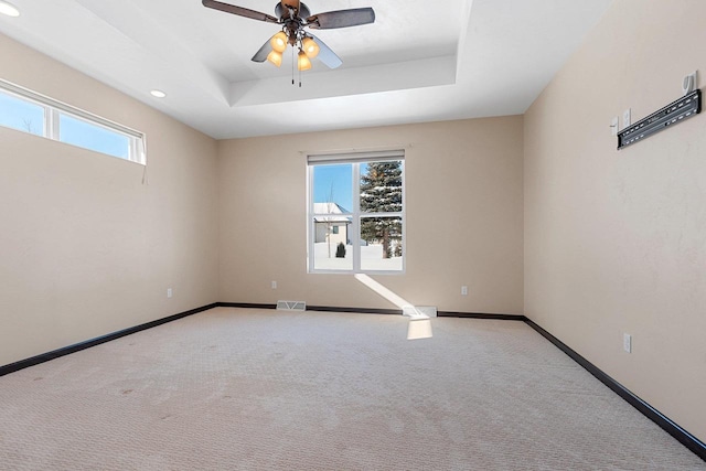 carpeted empty room with a tray ceiling and ceiling fan