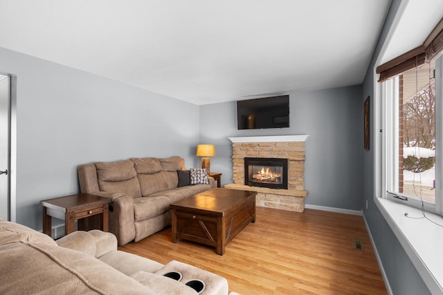 living room with light hardwood / wood-style floors, plenty of natural light, and a fireplace