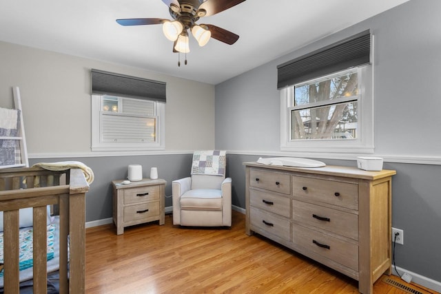 bedroom featuring a crib, light hardwood / wood-style floors, and ceiling fan