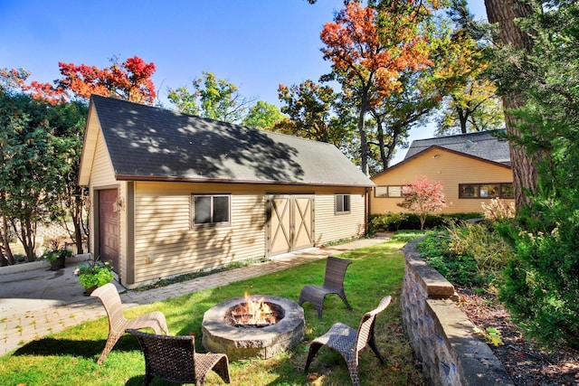 W5553 Oak Park Rd, Elkhorn, WI 53121 - rear view of house featuring a garage, a fire pit, an outdoor structure, and a lawn