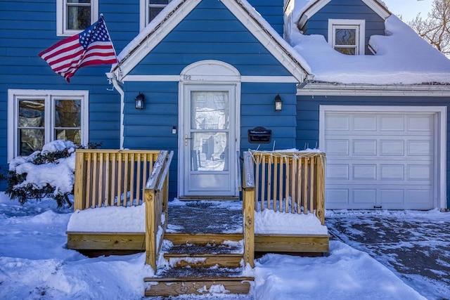 snow covered property entrance featuring a garage