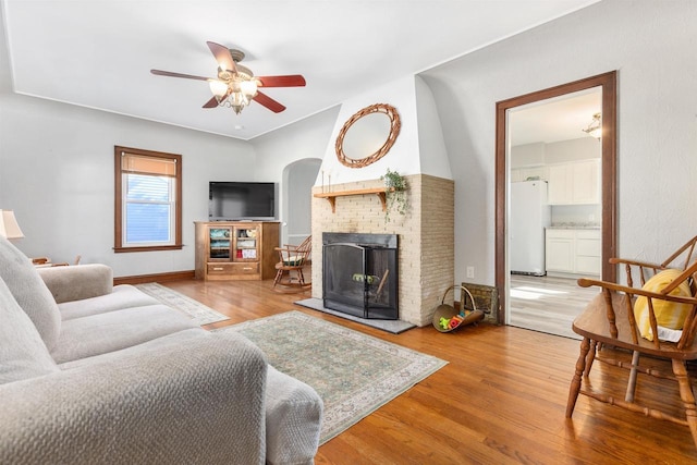 living room with light hardwood / wood-style flooring, ceiling fan, and a fireplace